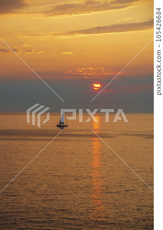 Morning sun and yacht on the horizon shining orange 105426684