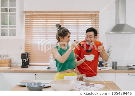 Funny husband fake to be happy with wife cooking. Funny couple in kitchen. 105429446