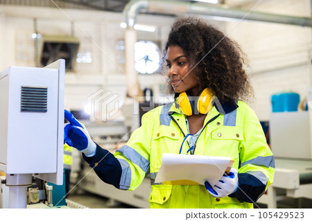 woman worker work control operate CNC wood milling machine in wood furniture workshop. technician staff women working with modern industry machine 105429523