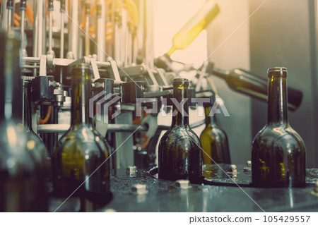 dark wine bottle water injection cleaning machine closeup in operation in winery factory 105429557