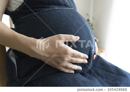 Belly of a pregnant woman sitting on a chair Belly of a pregnant woman sitting on a chair 105429988