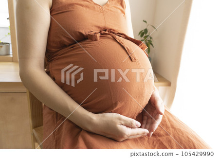 Belly of a pregnant woman sitting on a chair Belly of a pregnant woman sitting on a chair 105429990