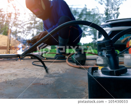 Close up power socket with a background of a worker welding metal for use in construction Close up power socket with a background of a worker welding metal for use in construction 105430033