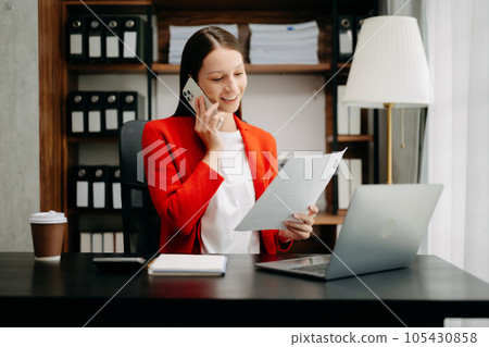 Caucasian female lawyer chatting online with client on laptop, smartphone  discussing details of lawsuit. in office 105430858