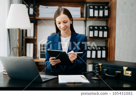 justice and law concept. Female judge in a courtroom  the gavel, working with smart phone and laptop and digital tablet computer on black  table 105431081
