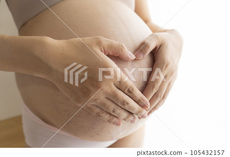 Pregnant woman putting her hand on her stomach with stretch marks and midline Pregnant woman putting her hand on her stomach with stretch marks and midline 105432157