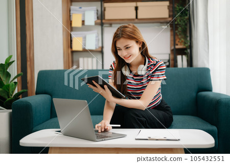 Female students note from the books at the Asian girl library sitting at sofa using laptop computer and tablet to search an online informations. Female students note from the books at the Asian girl library sitting at sofa using laptop computer and tablet to search an online informations. 105432551
