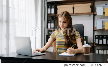 Beautiful Asian business woman typing laptop and tablet Placed at the table at home office.. 105432613