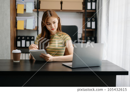 Beautiful Asian business woman typing laptop and tablet Placed at the table at home office.. 105432615
