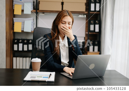 Overworked young Asian businesswoman office worker suffering from neck pain after had a long day at her office table. office syndrome concept 105433128