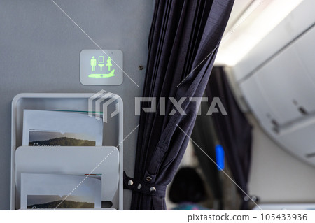 Lavatory signage on airplan cabin wall lighted green suggests it is not occupied 105433936