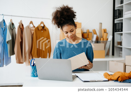 Young African business owner woman prepare parcel box and standing check online orders for deliver to customer on tablet, laptop Shopping Online concept. in office Young African business owner woman prepare parcel box and standing check online orders for deliver to customer on tablet, laptop Shopping Online concept. in office 105434544