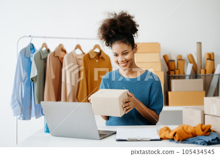 Young African business owner woman prepare parcel box and standing check online orders for deliver to customer on tablet, laptop Shopping Online concept. in office Young African business owner woman prepare parcel box and standing check online orders for deliver to customer on tablet, laptop Shopping Online concept. in office 105434545