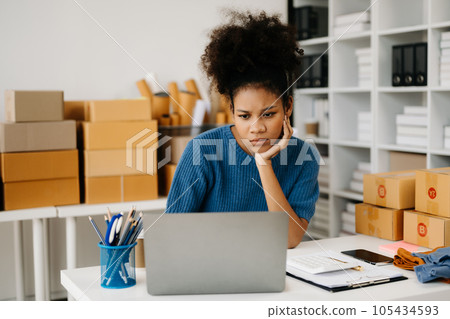 Calm curly brunette dark skinned woman on desk in modern office of fashion designer and holds tablet and smartphone. Calm curly brunette dark skinned woman on desk in modern office of fashion designer and holds tablet and smartphone. 105434593
