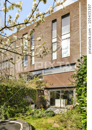 an outside view of a brick building with white flowers on the front and trees in the foregrounding area 105435397