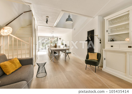a living room with white walls and wood flooring in the center of the room, there is a grey couch 105435414