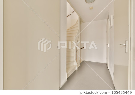 an empty hallway with white walls and grey flooring the room is well lit by daylight light from the window an empty hallway with white walls and grey flooring the room is well lit by daylight light from the window 105435449