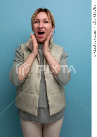 positive cheerful blond young woman in spring stylish look smiling on studio background 105435765