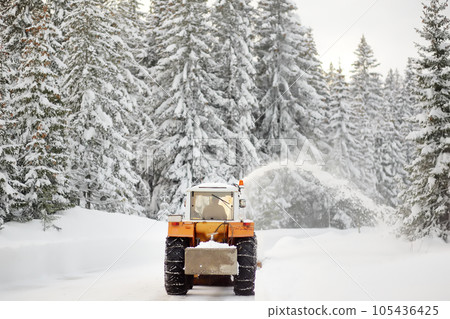 A snowplow truck clearing a snow-covered road in the European Alps while a snowstorm. Drifts and snow drifts during a snowfall. A snowplow truck clearing a snow-covered road in the European Alps while a snowstorm. Drifts and snow drifts during a snowfall. 105436425