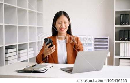 Successful Asian Businesswoman Analyzing Finance on Tablet and Laptop at Office Desk tax, report, accounting, statistics, and analytical research concept. 105436513