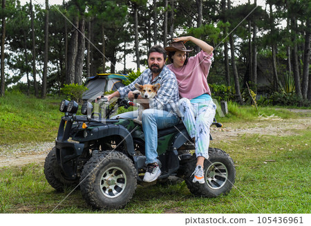 Portrait of young married couple sitting on a quad bike in the forest 105436961
