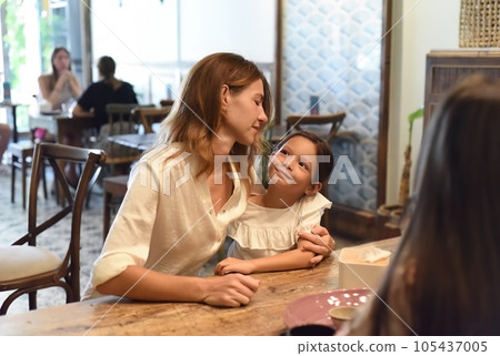 Little girl and her mother hugging and looking at each other in a cafe Little girl and her mother hugging and looking at each other in a cafe 105437005