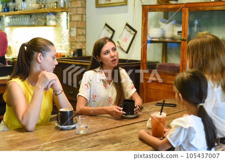 Female best friends talking and eating in a cafe Female best friends talking and eating in a cafe 105437007