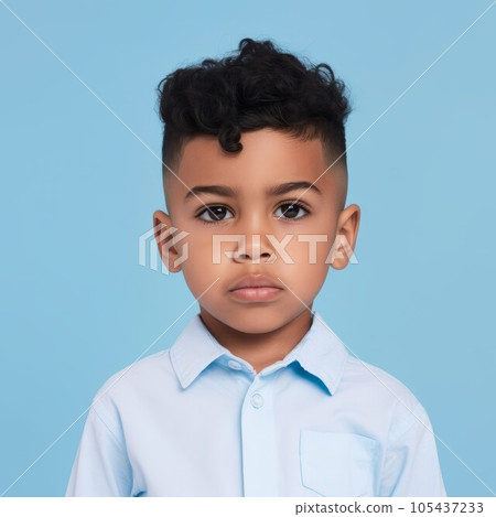 Portrait of a little Latin American boy with brown curly hair. Closeup face of a serious Latin child on a blue background looking at camera. Front view of an unsmiling kid in a blue shirt. 105437233