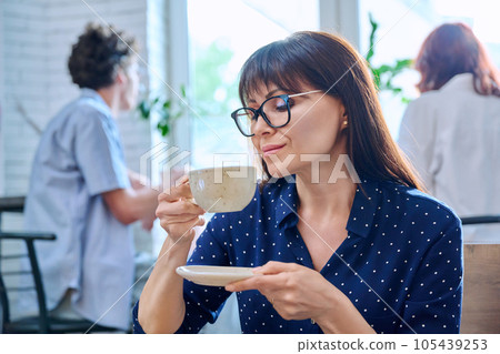 Relaxed middle aged woman enjoying fragrant cup of coffee, in coffee shop Relaxed middle aged woman enjoying fragrant cup of coffee, in coffee shop 105439253