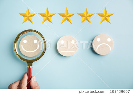 Magnifying glass held by hand selects happy smiley face icon among emotions. Good feedback rating, positive customer review. Experience, satisfaction survey. Certificate represents satisfaction. Magnifying glass held by hand selects happy smiley face icon among emotions. Good feedback rating, positive customer review. Experience, satisfaction survey. Certificate represents satisfaction. 105439607