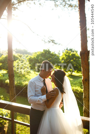 Lovely wedding couple at sunset. Bride, groom in wedding attire with bouquet of flowers. Romantic. 105444540