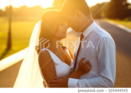 Lovely wedding couple at sunset. Bride, groom in wedding attire with bouquet of flowers. Romantic. Lovely wedding couple at sunset. Bride, groom in wedding attire with bouquet of flowers. Romantic. 105444545