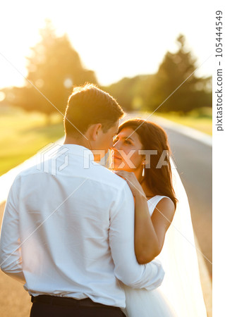 Lovely wedding couple at sunset. Bride, groom in wedding attire with bouquet of flowers. Romantic. 105444549
