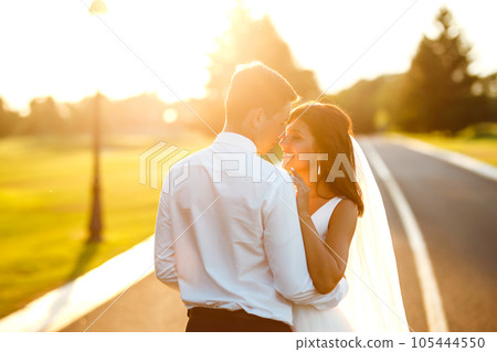 Lovely wedding couple at sunset. Bride, groom in wedding attire with bouquet of flowers. Romantic. Lovely wedding couple at sunset. Bride, groom in wedding attire with bouquet of flowers. Romantic. 105444550