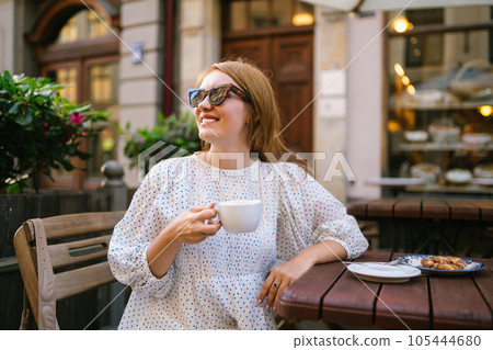 Tourist woman enjoys architecture of city streets with cup of coffee. Travel and vacation concept. Tourist woman enjoys architecture of city streets with cup of coffee. Travel and vacation concept. 105444680