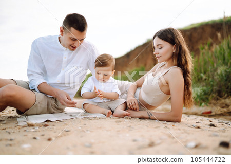 Cheerful young family with little baby boy spending time together on the beach. Cheerful young family with little baby boy spending time together on the beach. 105444722