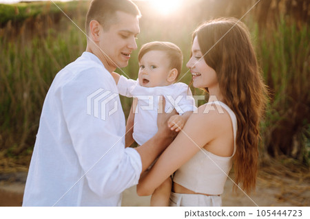 Cheerful young family with little baby boy spending time together on the beach. Cheerful young family with little baby boy spending time together on the beach. 105444723