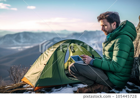 Young professional photographer with computer works in the snowy winter forest. Mountain's camping for work at distance. AI Generative 105445728