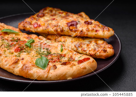 Delicious oven fresh flatbread pizza with cheese, tomatoes, sausage, salt and spices Delicious oven fresh flatbread pizza with cheese, tomatoes, sausage, salt and spices 105445885