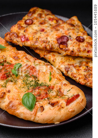 Delicious oven fresh flatbread pizza with cheese, tomatoes, sausage, salt and spices Delicious oven fresh flatbread pizza with cheese, tomatoes, sausage, salt and spices 105445889