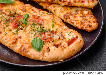 Delicious oven fresh flatbread pizza with cheese, tomatoes, sausage, salt and spices 105445897
