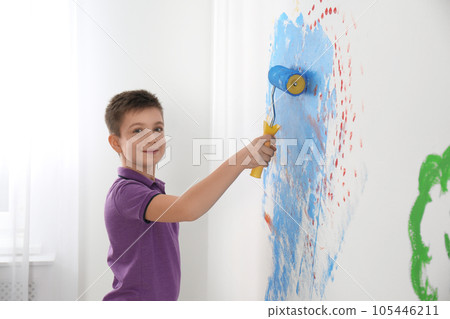 Little child painting wall with roller brush indoors Little child painting wall with roller brush indoors 105446211