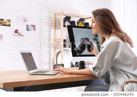 Professional photographer with camera working at table in office 105446245