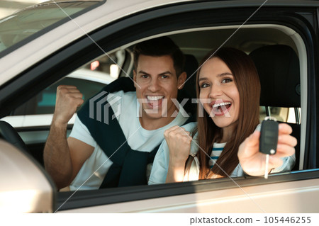Happy couple with car key sitting in modern auto at dealership Happy couple with car key sitting in modern auto at dealership 105446255