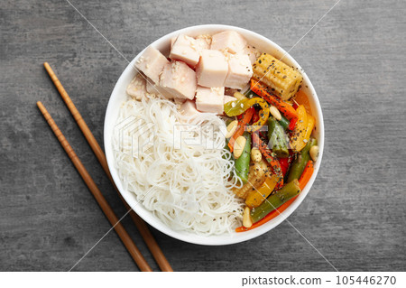 Tasty cooked rice noodles with chicken and vegetables on grey table, flat lay Tasty cooked rice noodles with chicken and vegetables on grey table, flat lay 105446270