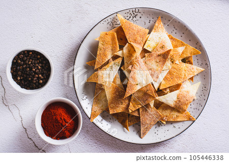 Close up of piquant chips with paprika and dill from pita bread on a plate top view Close up of piquant chips with paprika and dill from pita bread on a plate top view 105446338