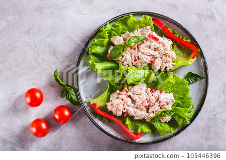Close up of canned tuna salad with vegetables on lettuce leaves on a plate top view 105446396