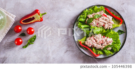Canned tuna salad with pepper and egg on lettuce leaves on a plate top view web banner 105446398