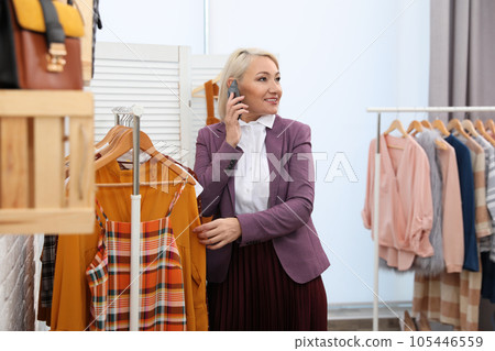 Female business owner talking on phone in boutique Female business owner talking on phone in boutique 105446559