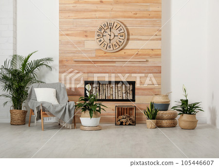 Beautiful plants and armchair near wooden wall. Stylish interior design 105446607